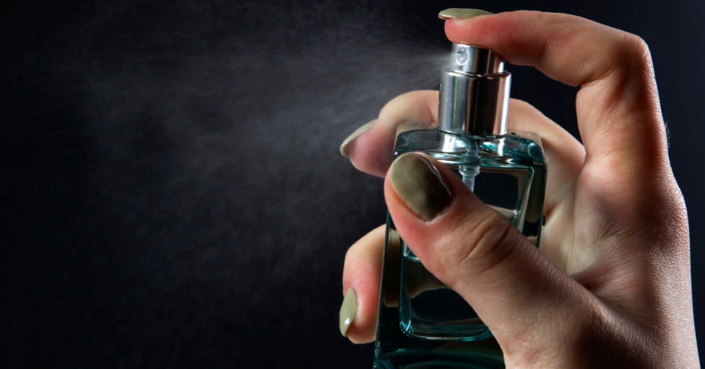 A close-up of a hand spraying perfume, showcasing the fine mist of fragrance. Ambrofix-based